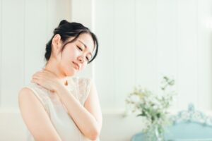肩こりがひどくて、肩を抑えている女性の写真